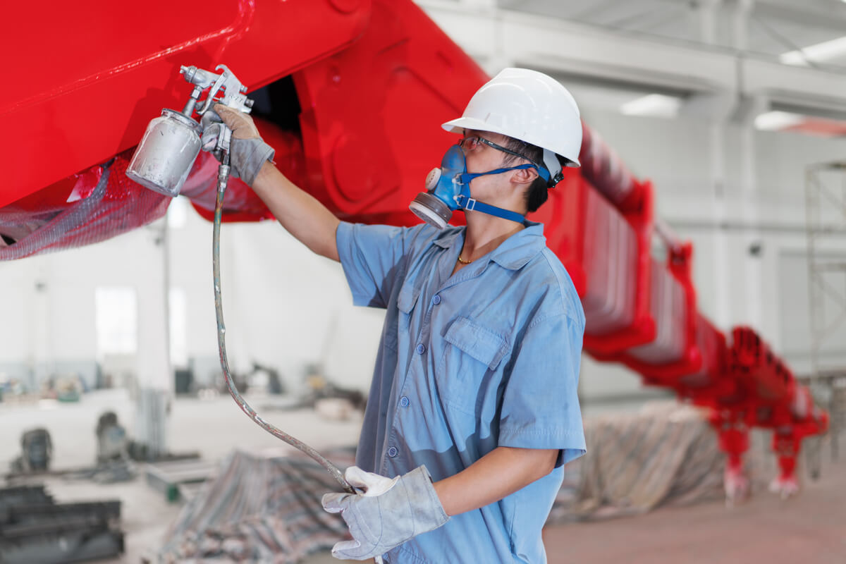 male-worker-spray-painting-a-crane-arm-red-in-fact-LNRSV8L